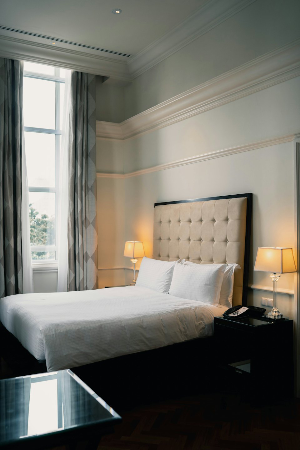 Hotel bedroom with a large bed and warm lamps.