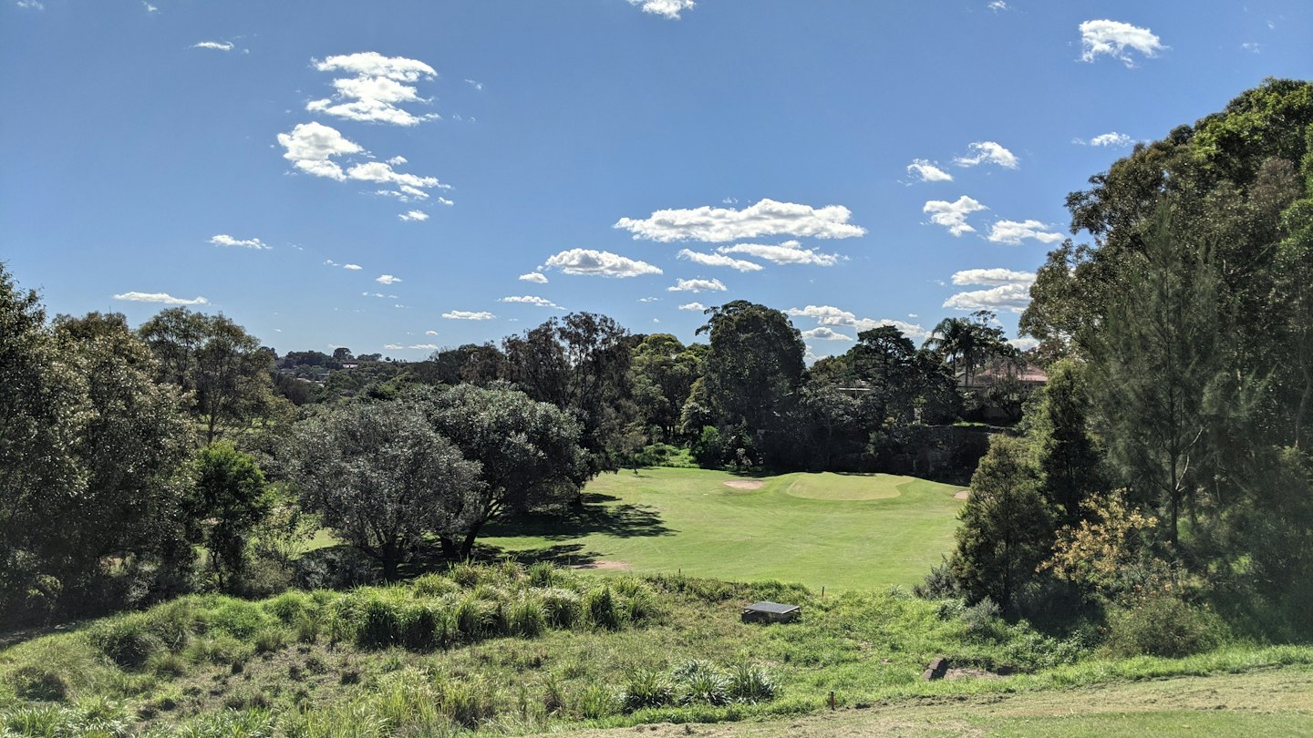 Lush green golf course fairways surrounded by dense forest trees.
